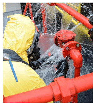 A person in a yellow hazmat suit repairs a leaking pipe during an onsite Hazwoper Ohio safety training session